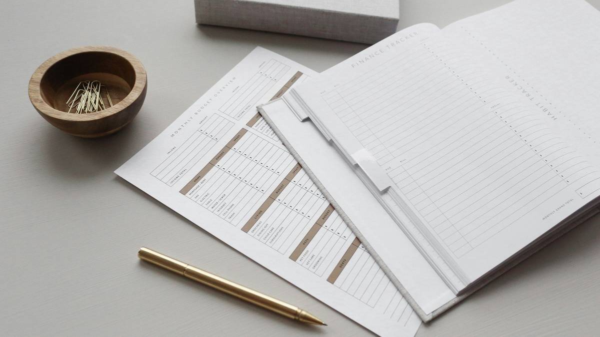A person reviewing medical bills while writing in a budgeting notebook, illustrating a savings plan for health expenses